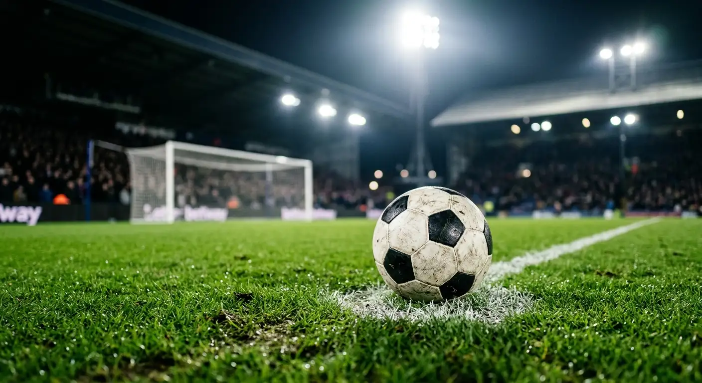 Et nærbillede af en fodbold på pletten i et målfelt under skarpe projektører